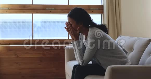 沮丧的非洲女人在家里坐在沙发上感到不安视频的预览图