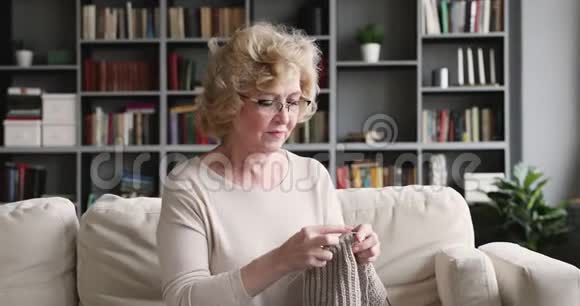 在家里坐在沙发上编毛衣的成熟的女人很放松视频的预览图
