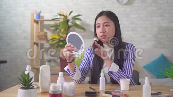 一位不满的亚洲年轻女子在客厅化妆的肖像视频的预览图
