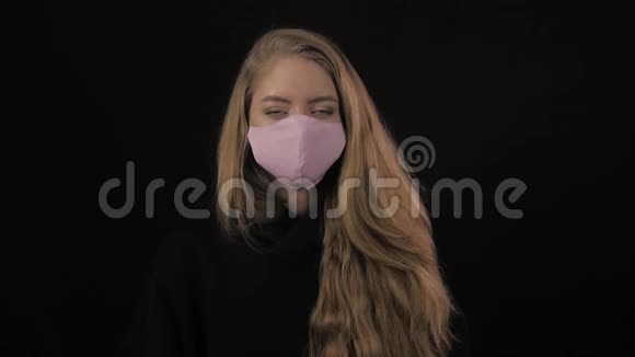 金发的年轻女人摘下一个粉红色的医疗面具孤立在黑色背景上保健和医疗概念视频的预览图