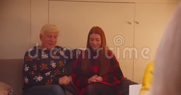 祖父孙女红发女孩惊喜的微笑坐在沙发上圣诞礼物给予安慰视频的预览图