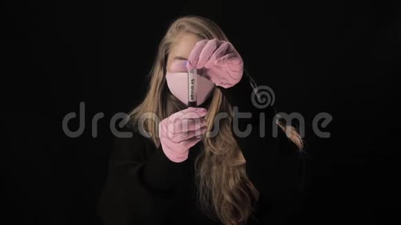 一个戴着黑色面具的女孩打开一个带血的试管上面写着covid19然后把它倒了孤立于黑色视频的预览图