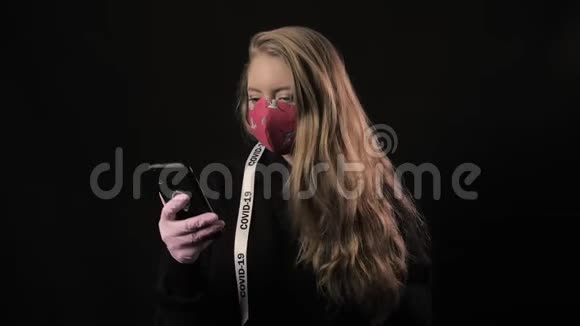 带着白色丝带的女孩和红色面具中的铭文Covid19在智能手机上自拍孤立于黑色视频的预览图