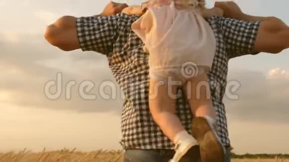 快乐的孩子和父亲正在一片成熟的麦子里玩耍幸福的家庭和童年的概念女儿和父亲视频的预览图
