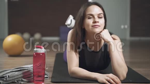 一位年轻貌美的女子训练后躺在垫子上的肖像视频的预览图