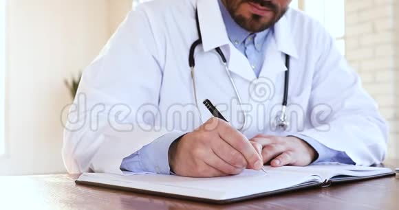 男医生穿白大褂在笔记本上写处方特写视频的预览图