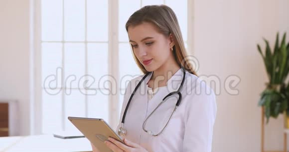 女医生身穿白色制服手持数码平板电脑视频的预览图