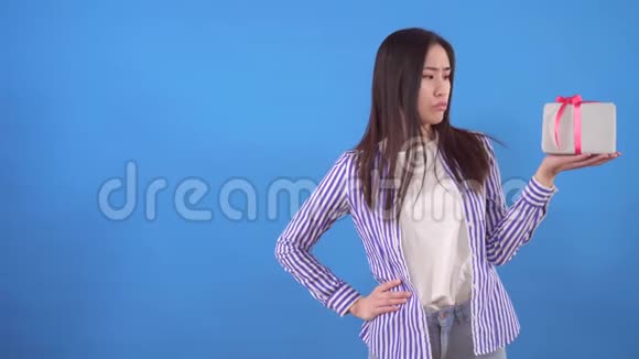 年轻的亚洲女人得到了一份巨大的礼物而不是蓝色背景的小礼物视频的预览图