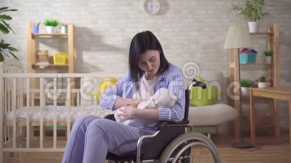 一个年轻的残疾妇女和一个新生儿看着镜头微笑的肖像视频的预览图