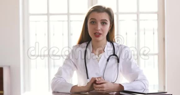 年轻的女医生穿着白色制服看着镜头视频的预览图
