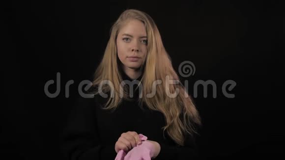 金发的年轻女人戴上粉红色的医用手套孤立在黑色背景上保健和医疗视频的预览图