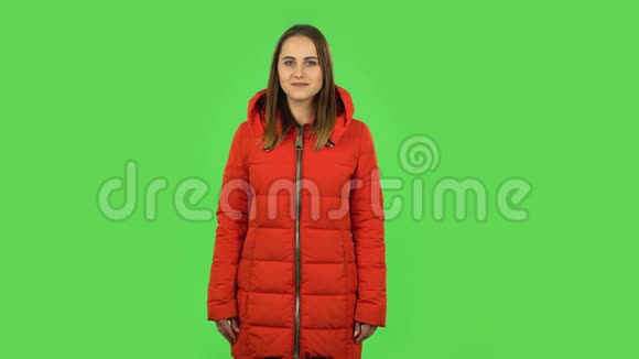 穿着红色羽绒服的可爱女孩在看镜头时风骚地笑着绿色屏幕视频的预览图