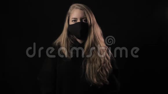 戴着黑色面具的女孩拿着一条丝带上面写着Covid19孤立在黑色背景上保健和医疗视频的预览图