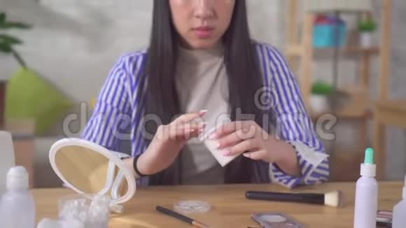 年轻漂亮的亚洲女人在家里的餐桌上使用面霜视频的预览图