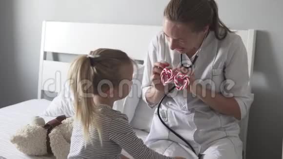 医生以心脏的形式用滑稽的眼镜听小病人背部的听诊器视频的预览图