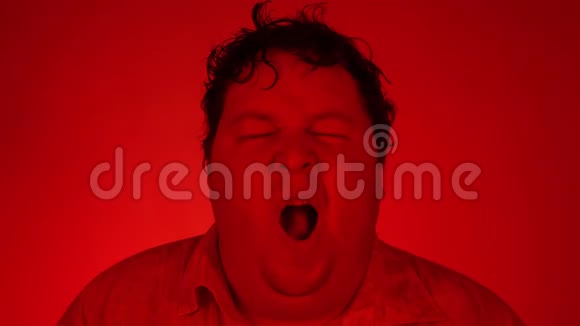 疲惫的欧洲男人打哈欠张开嘴红色照明帅哥想在红色背景下睡觉视频的预览图