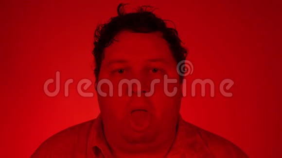 一位年轻漂亮男子的肖像露出舌头面部表情红色灯光视频的预览图