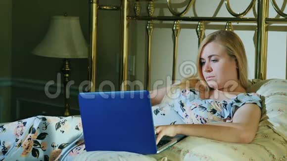 有笔记本电脑的年轻女子躺在卧室的床上视频的预览图