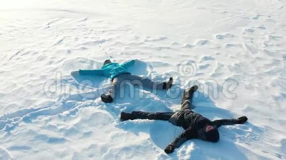 一家人在森林的空地上做一个雪天使的身影一个女孩和一个男孩躺在空中摄影视频的预览图