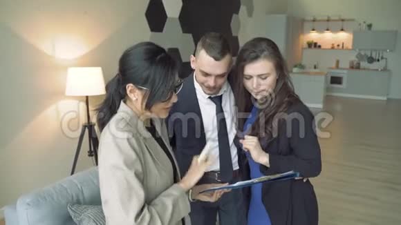 专业房地产经纪人给一对年轻夫妇公寓或房子的钥匙视频的预览图