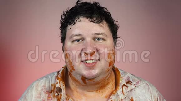 一顿又一顿又胖又脏的人脸上撒着番茄酱红色背景不健康概念视频的预览图