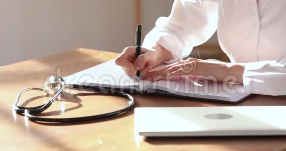 女医生穿着白色制服在笔记本上做笔记特写视频的预览图