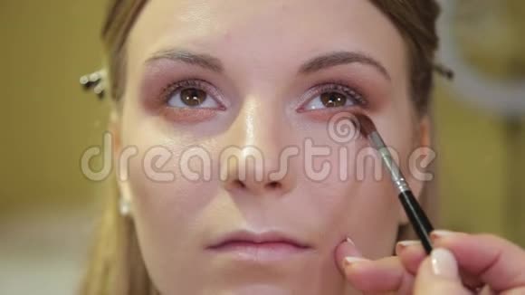 专业化妆师用刷子将眼影应用于美容院的客户视频的预览图