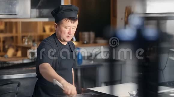 忙碌的亚洲厨房工人穿着黑色衣服在煎锅里做饭中型摄影机视频的预览图