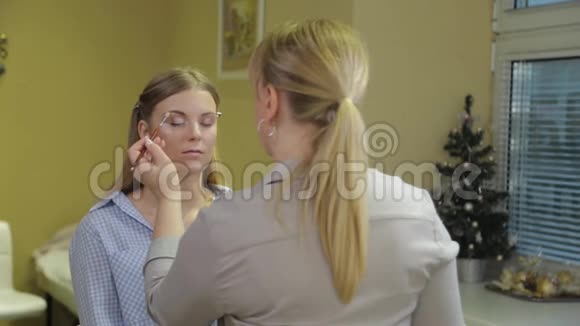 专业化妆师用刷子将眼影应用于美容院的客户视频的预览图