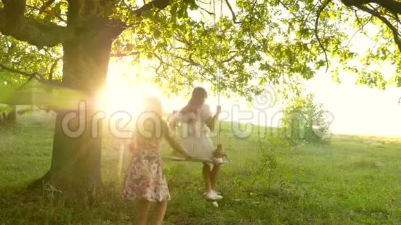孩子们在阳光下在橡树枝上摇摆飞行的梦想快乐童年的概念漂亮的女孩视频的预览图