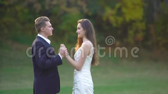 快乐的新婚夫妇在公园阳光明媚的日子里互相享受男人吻他心爱的人的手视频的预览图