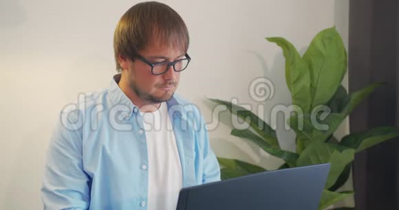 戴眼镜的商人带着笔记本电脑在办公室喝咖啡或茶商业人员和技术概念视频的预览图