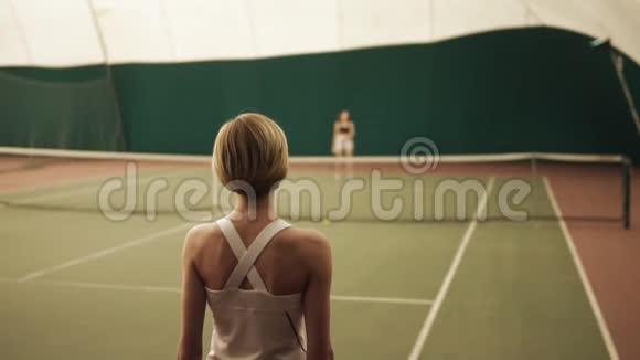 一名女网球运动员在网球场用球拍击球的后侧慢动作镜头视频的预览图