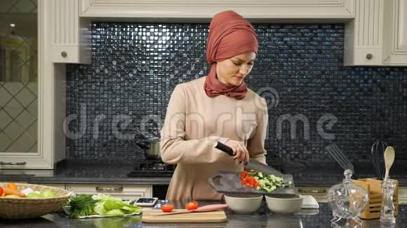 戴头巾的有魅力的家庭主妇把切好的新鲜蔬菜放进深盘里准备清真食品视频的预览图