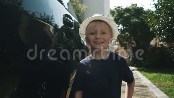 一个戴帽子的男孩站在车旁边笑视频的预览图