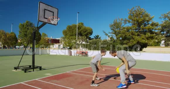 爸爸和儿子在街上打篮球向篮子里扔一个球视频的预览图