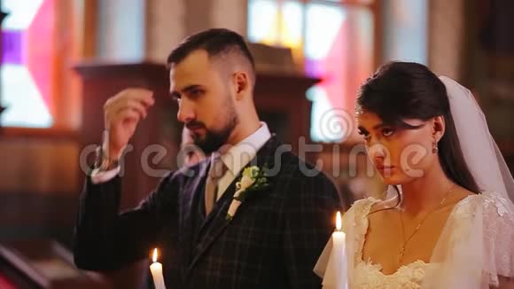 时尚漂亮的新婚夫妇新娘和新郎手持蜡烛在婚礼上接受洗礼视频的预览图