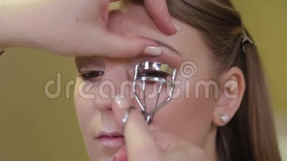 化妆师在模特的眼睛上化妆用化妆设备工具扭转睫毛埃拉什视频的预览图