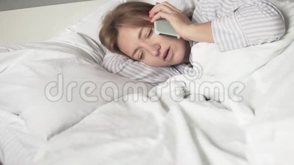 早上睡觉的女人用手机说话视频的预览图