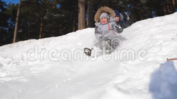 孩子们骑在雪山上慢动作雪的冬季景观户外运动视频的预览图
