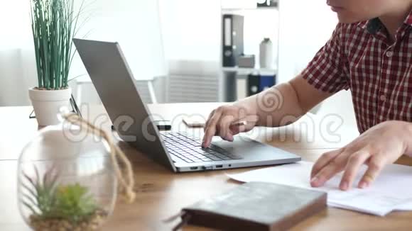 男人用手提电脑做纸质文件视频的预览图