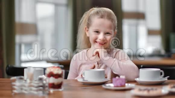 女婴在咖啡桌上摆着茶和美味的肖像近距离拍摄4k红色相机视频的预览图