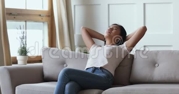 席琳年轻的亚洲女人休息伸展坐在沙发上视频的预览图