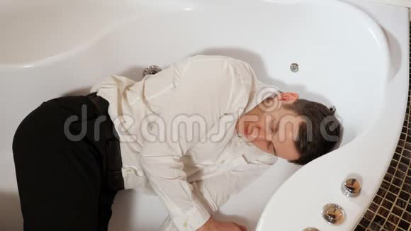 穿裤子和衬衫的人正睡在浴室里视频的预览图