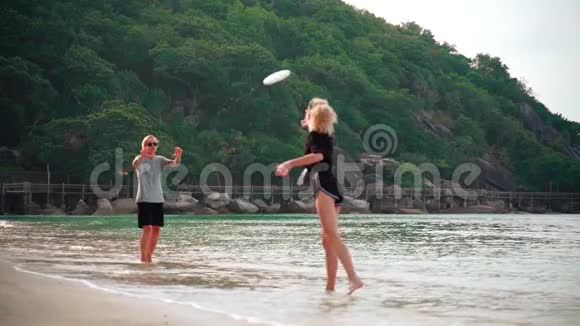 一个阳光明媚的日子两个年轻的女人在热带海滩扔飞盘视频的预览图
