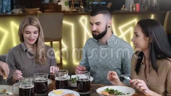 一群快乐的男人和女人一起在现代酒吧放松用餐中型摄影机视频的预览图