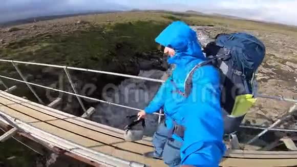 微笑青年男子徒步穿越崎岖的冰岛地形在Fimvorduhals上大风达到每秒30米视频的预览图