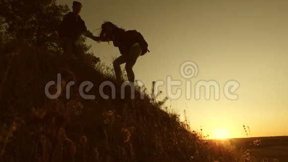 日落时分自由旅行者双手从山上下来男游客牵着女游客的手视频的预览图