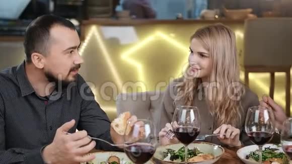 四个微笑的年轻人坐在酒吧里吃着新鲜美味的食物中型摄影机视频的预览图