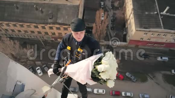 穿制服的男式职业登山者失视高挂在高楼大厦上方的电缆上美丽视频的预览图